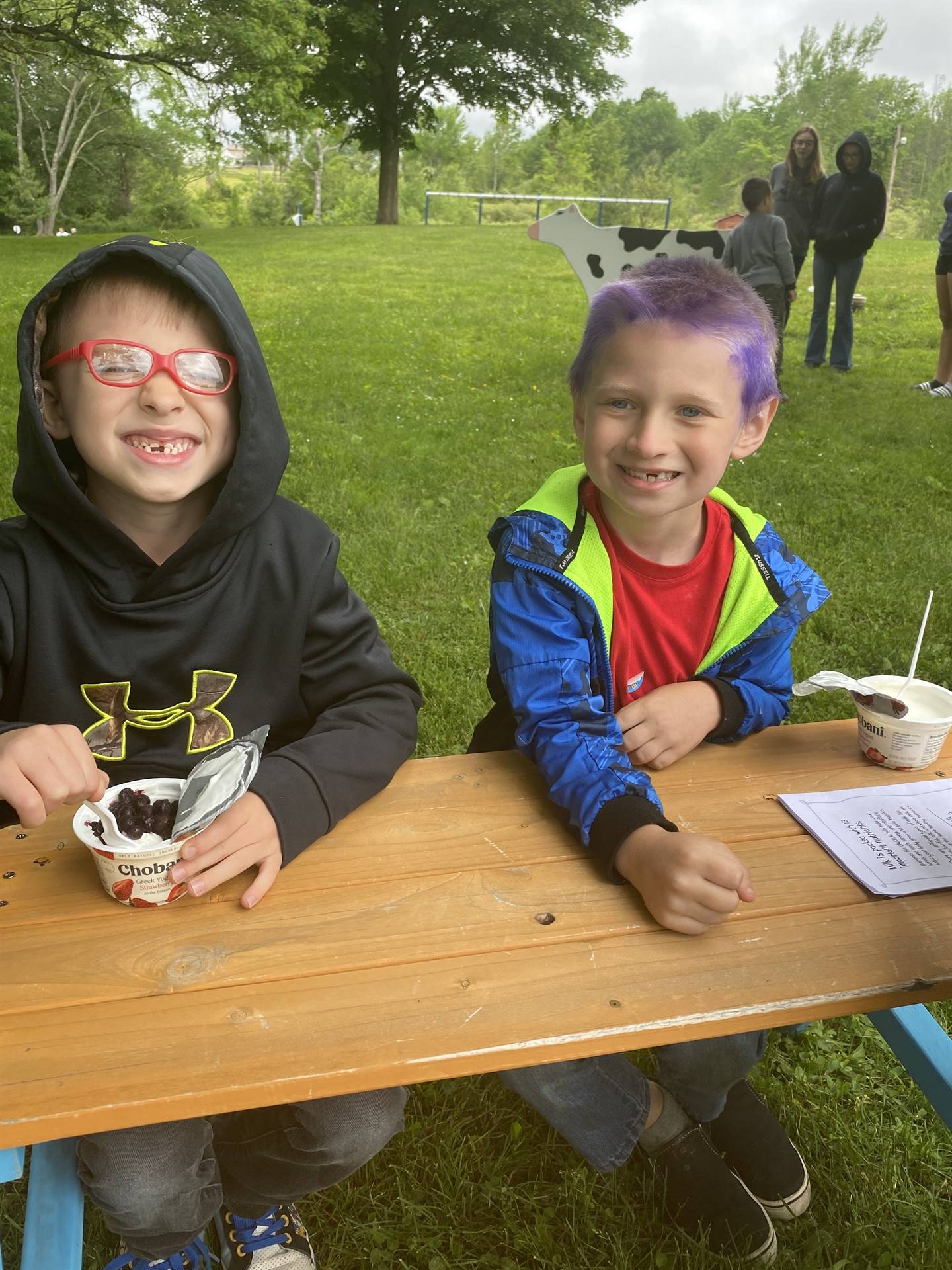 students at picnic tables eating yogurt.