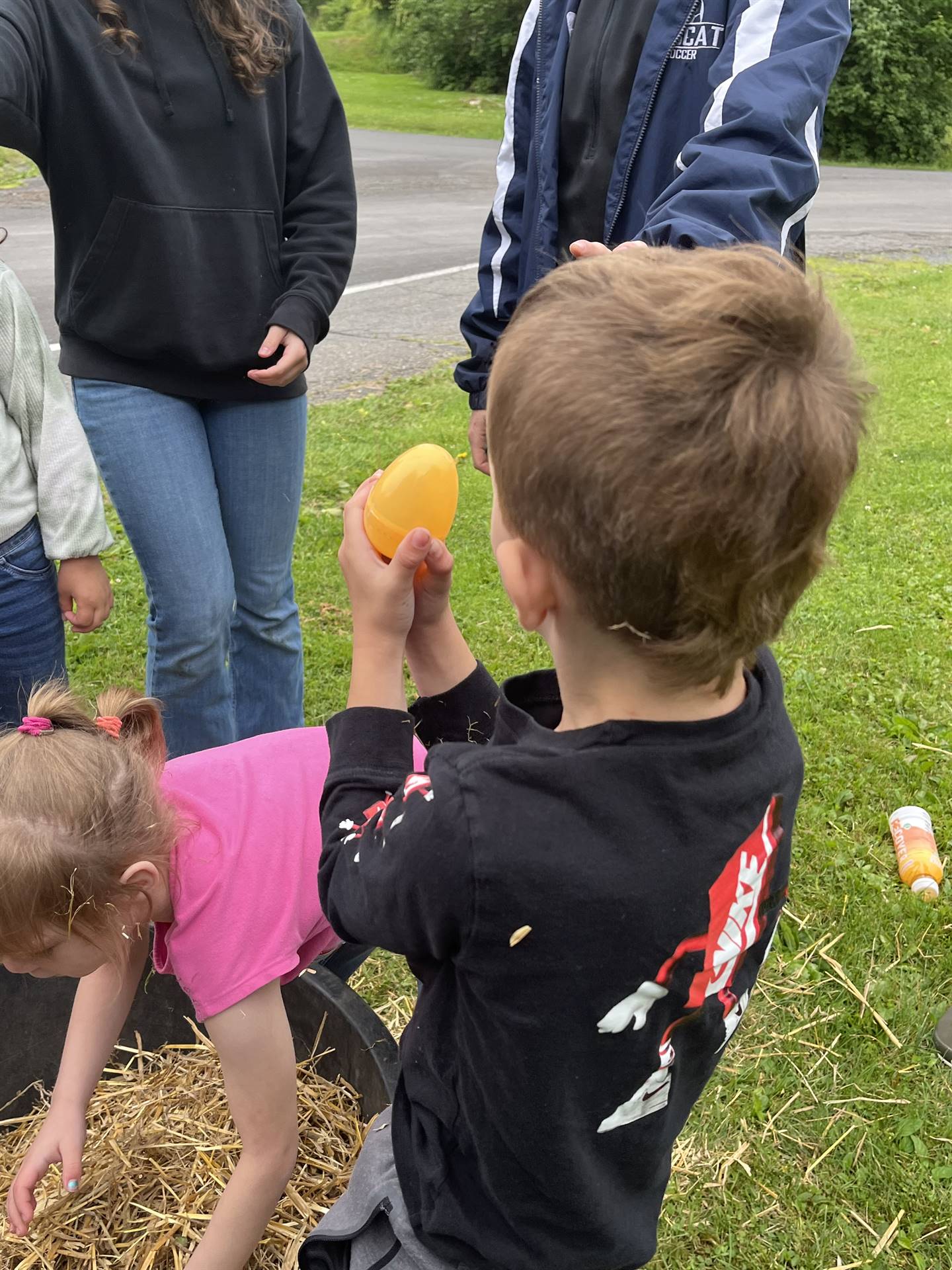 student holding up an egg found in a tub of straw.