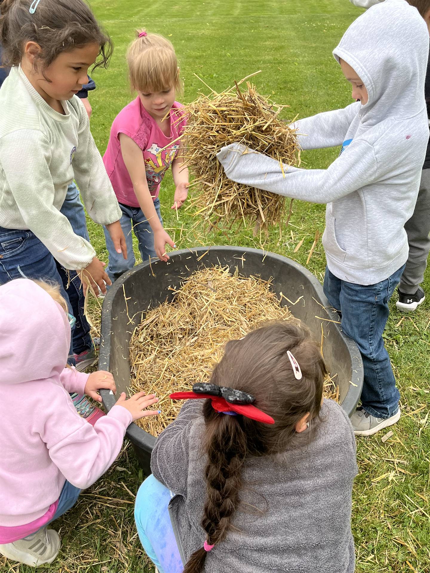  students digging for eggs found in a tub of straw.