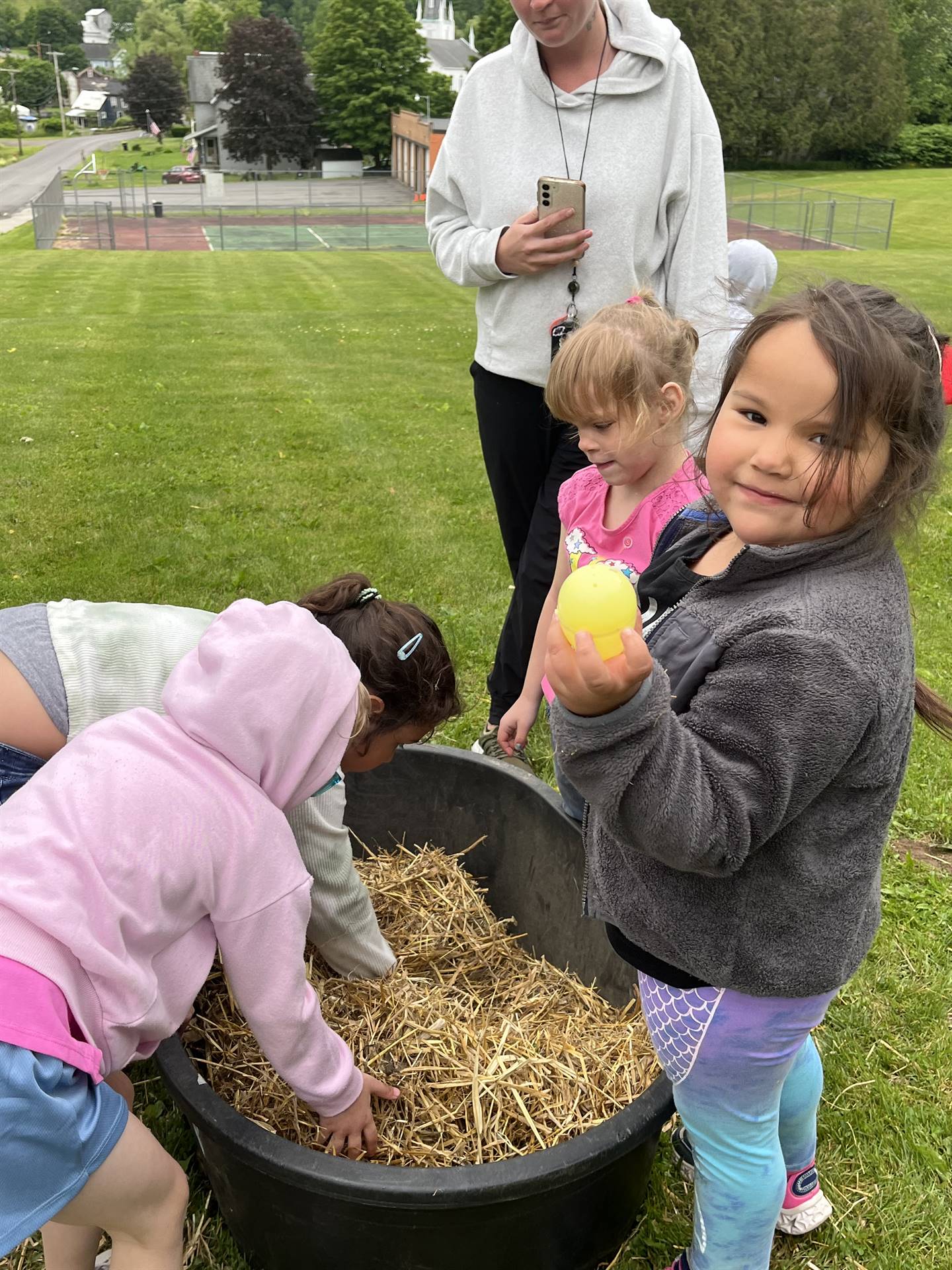 students digging for eggs found in a tub of straw.