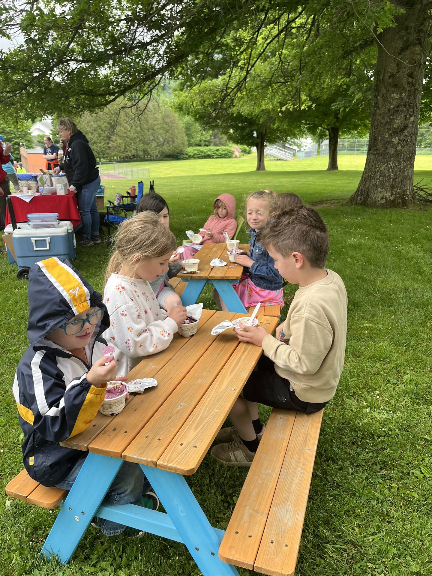 students eating yogurt snack at picnic tables.
