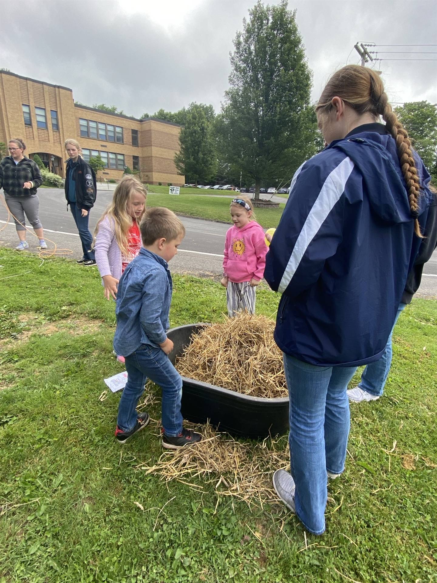 students gathered around a tub filled with straw.