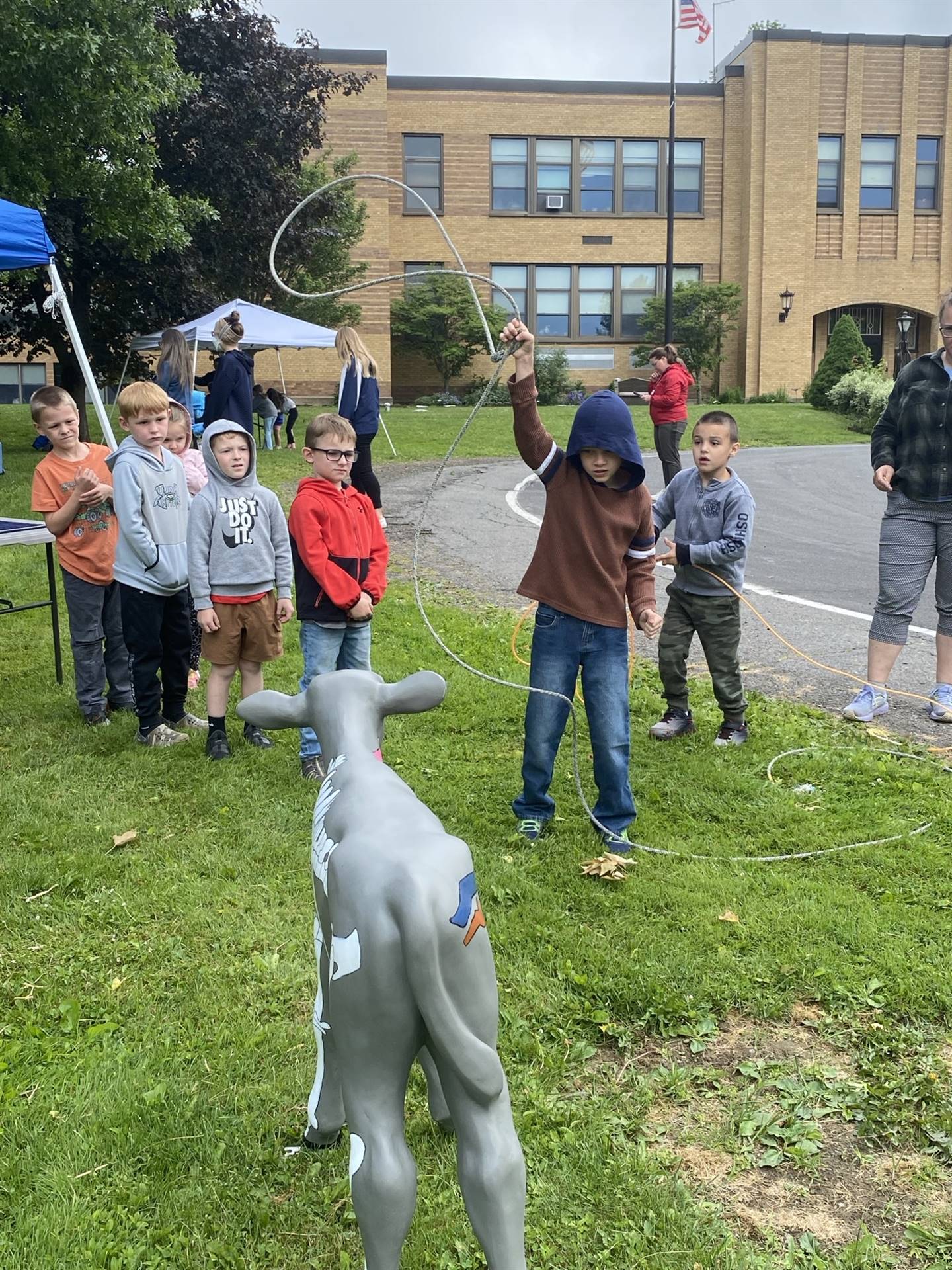 students pretending to lasso a cow statue