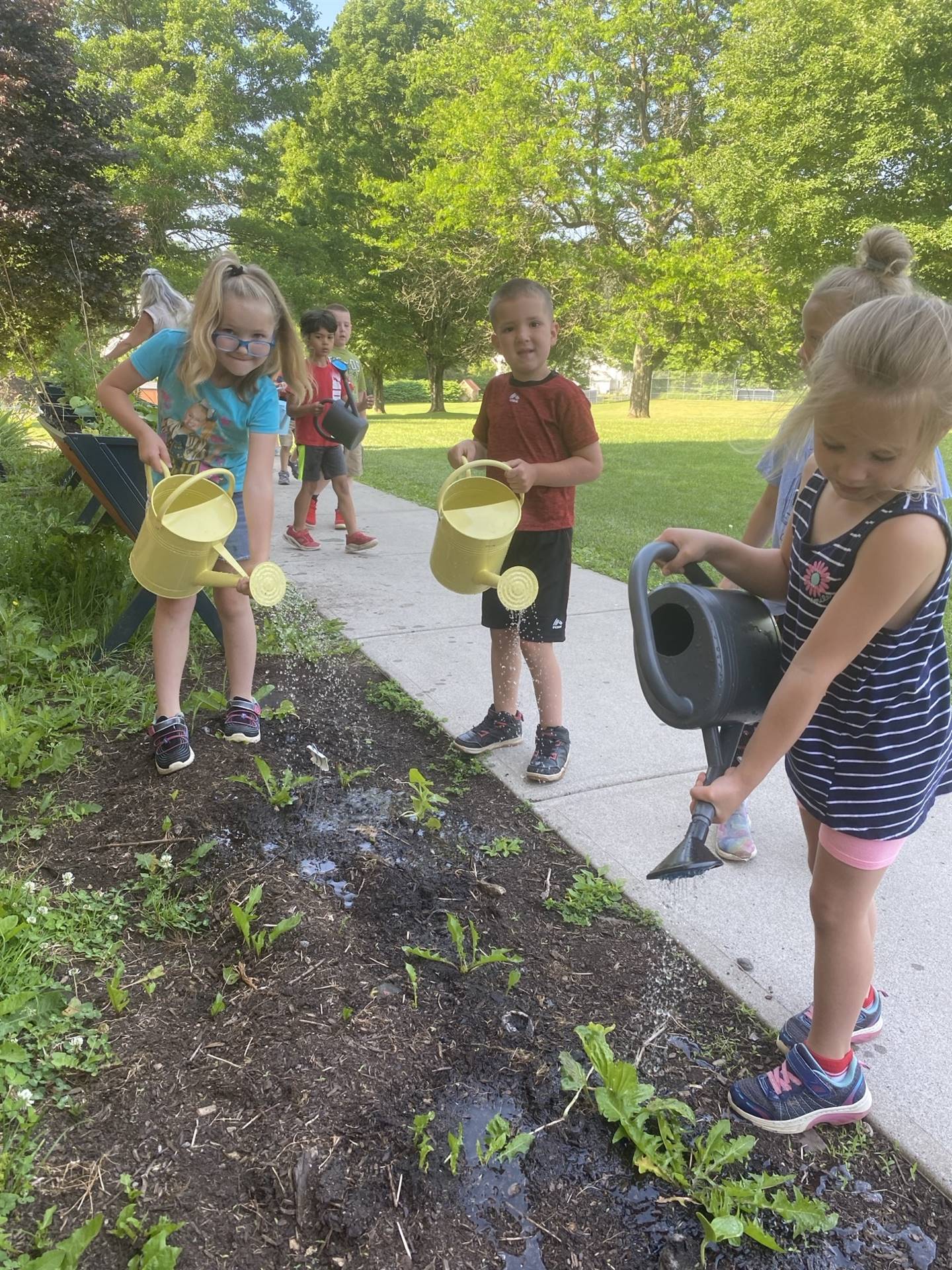 students with watering cans outside