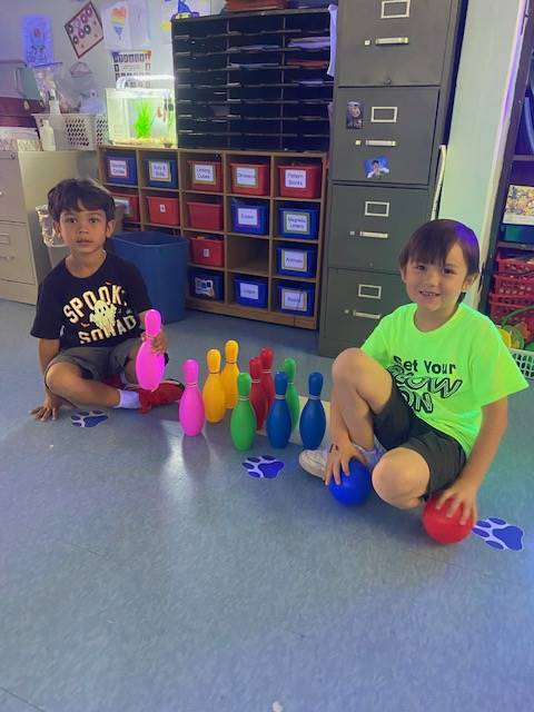 2 students with multicolored bowling balls between them