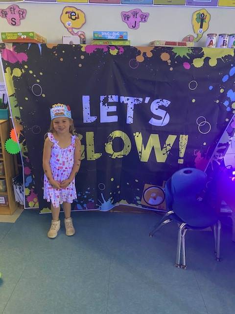 student in front of "Let's Glow" sign