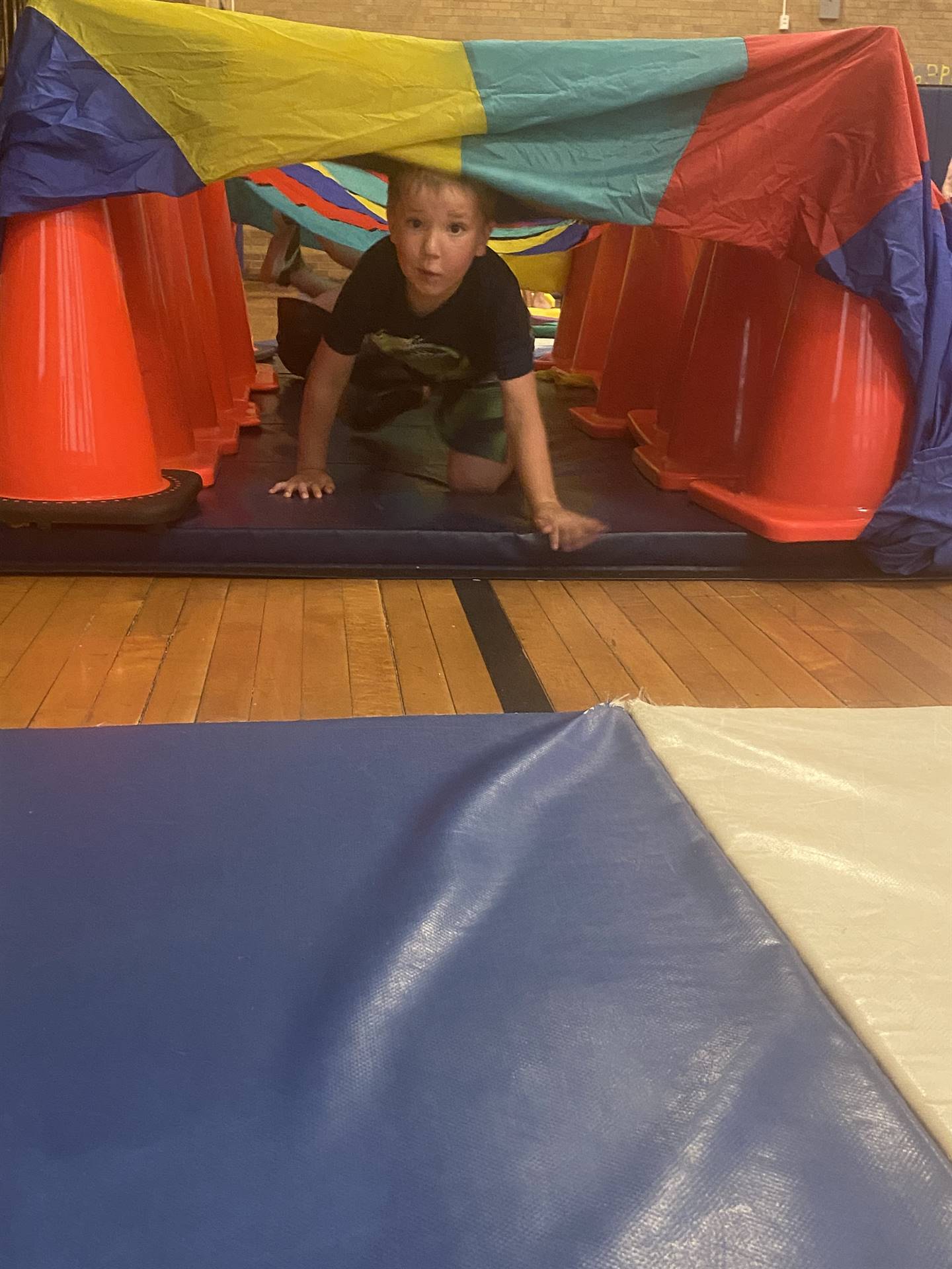 student crawling under tunnel