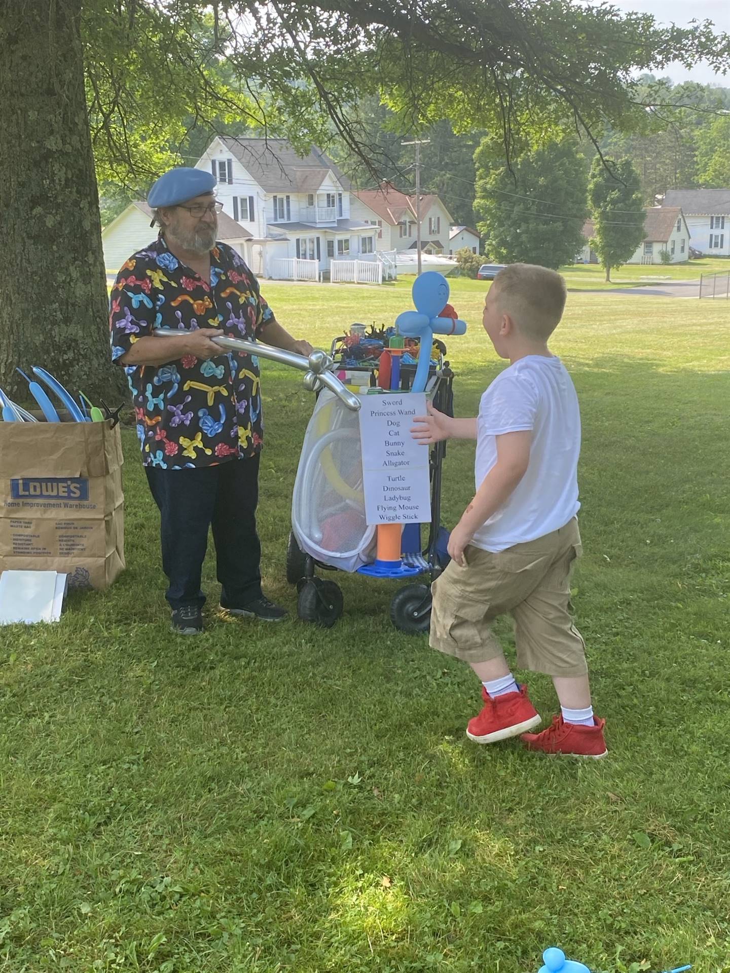 a man blows up balloons for a child out doors.