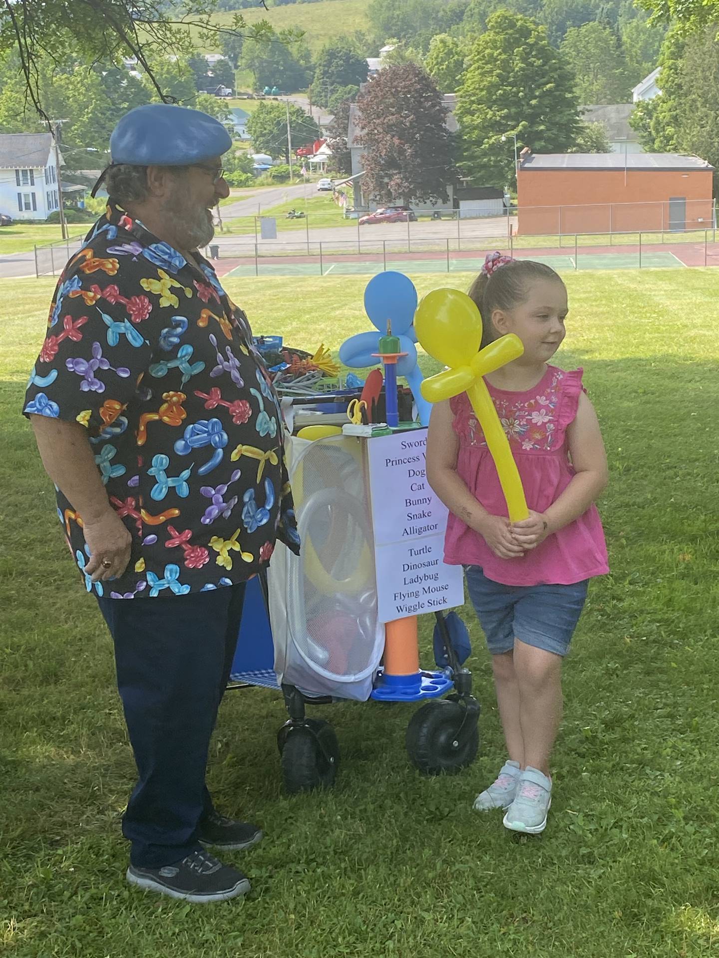 a man blows up balloons for a child out doors.