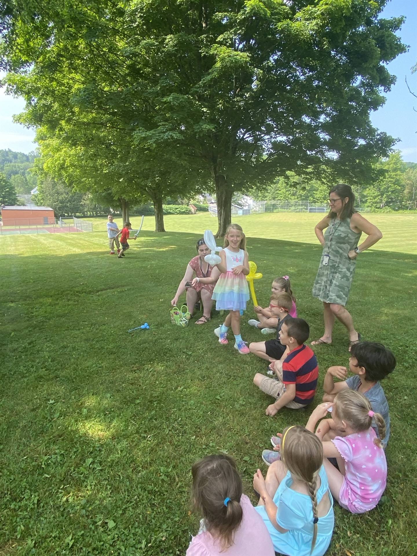 Children sit on the grass with their special balloons.