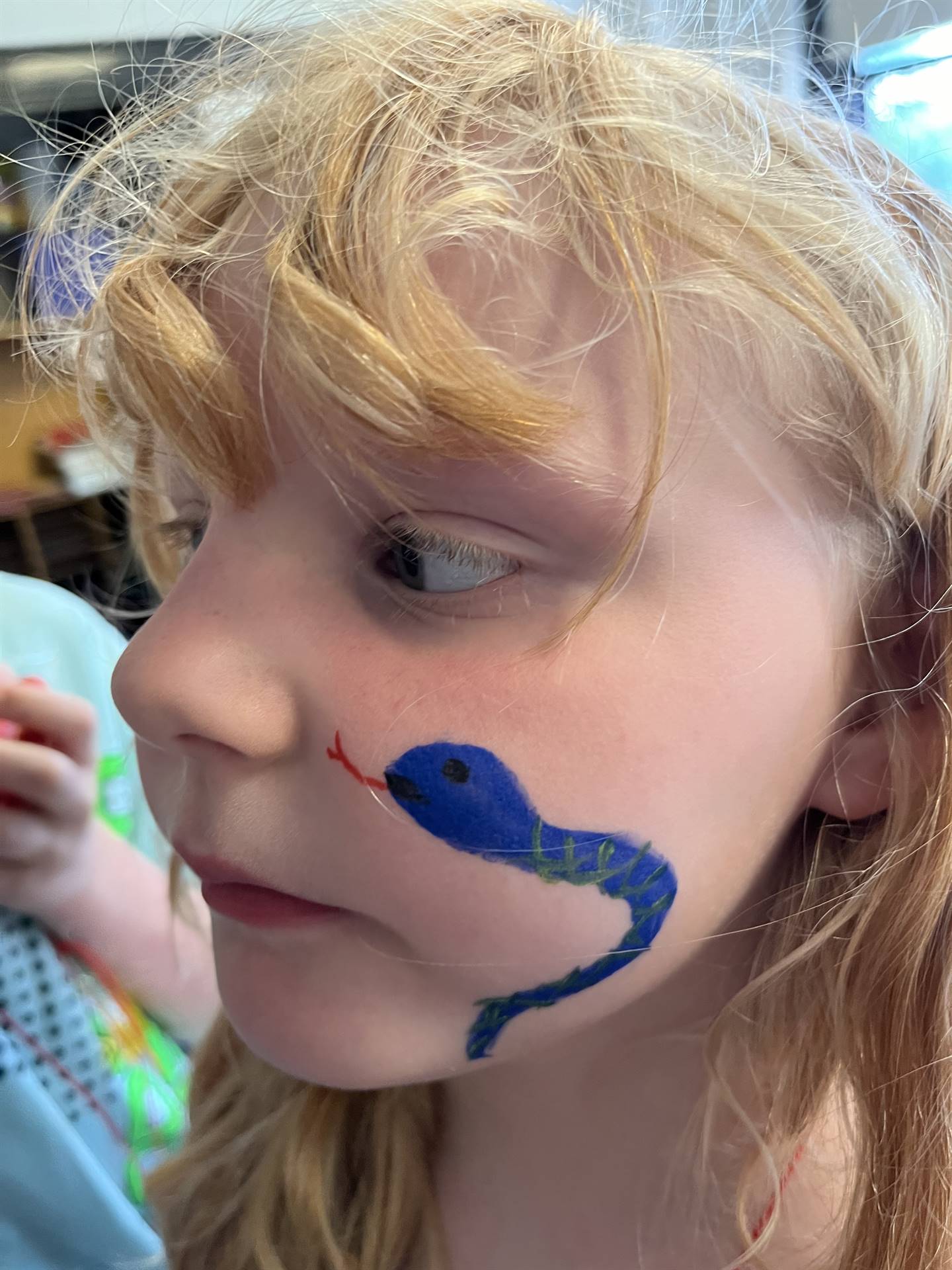 student with blue painted snake on her cheek
