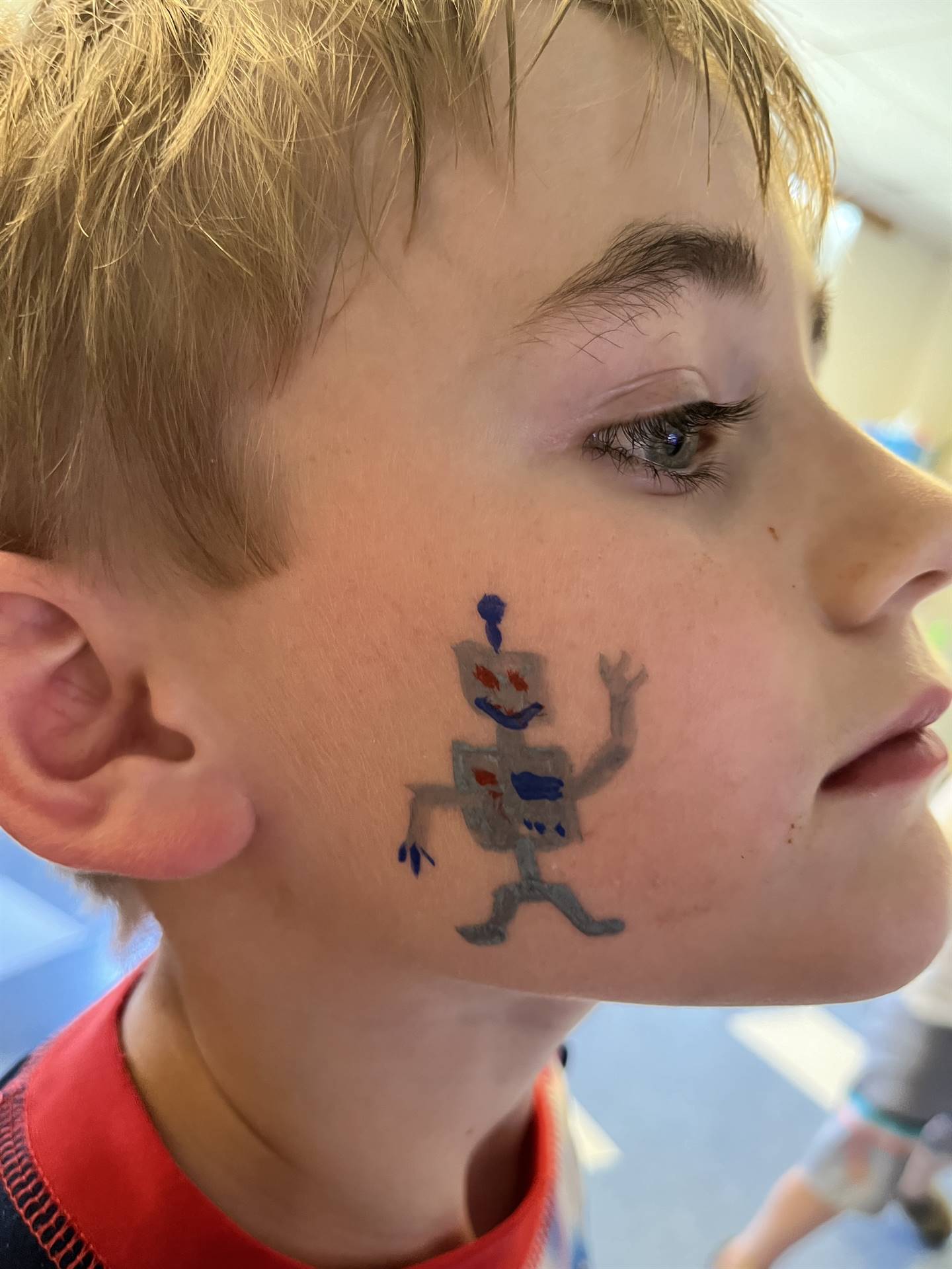 student with robot painted on his cheek.
