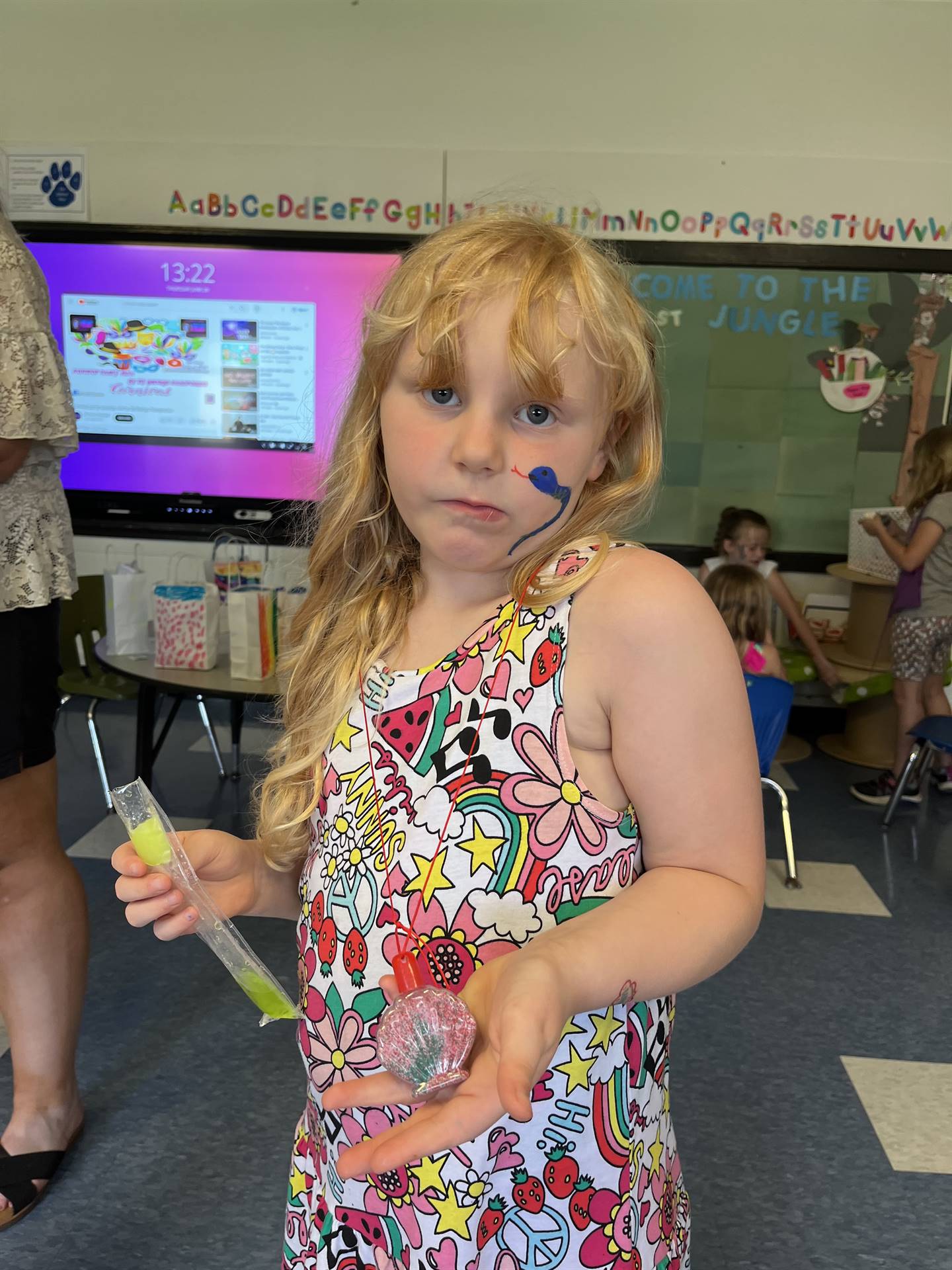 student holds up a sand art necklace she made.