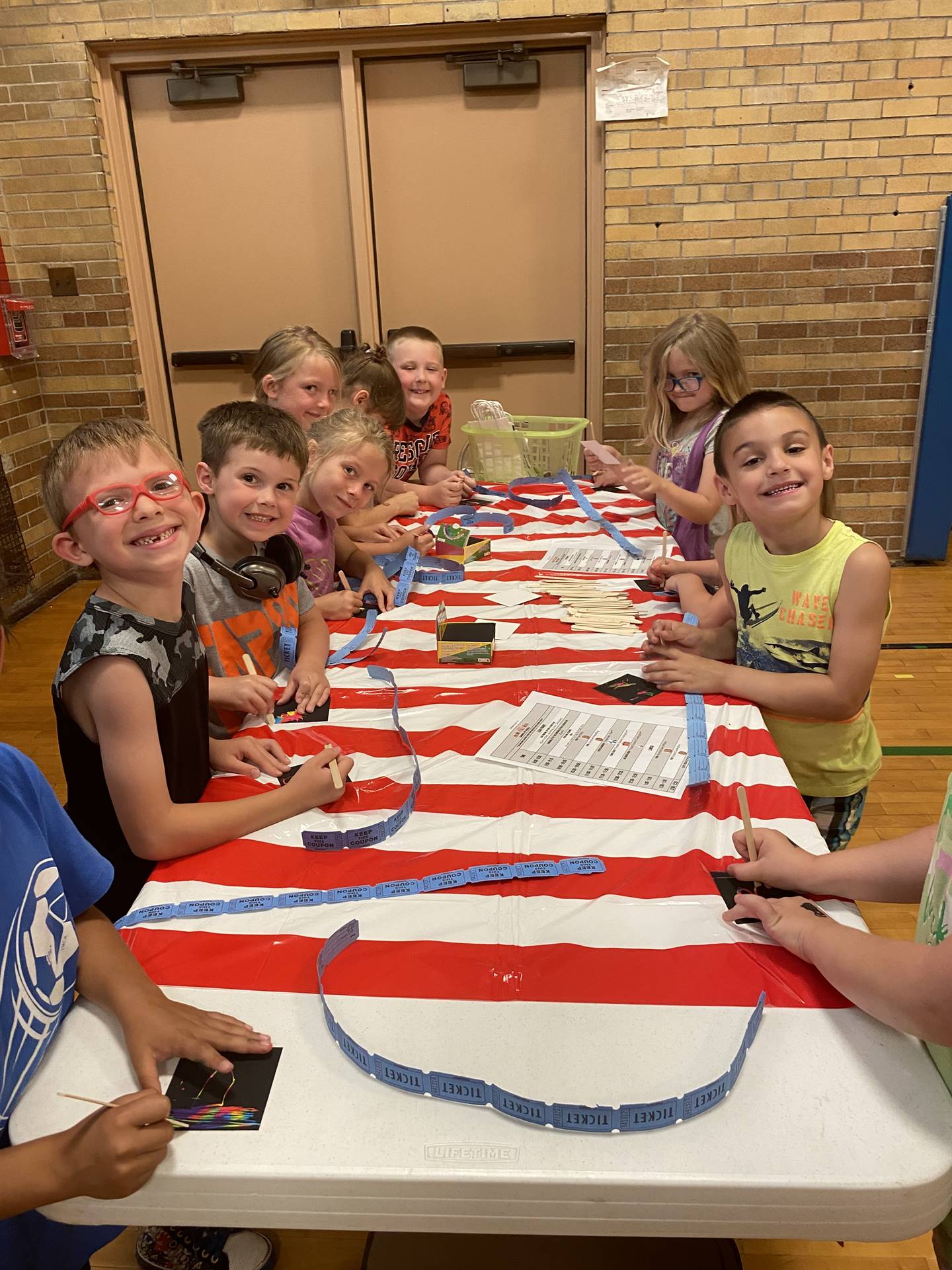 students sitting at a white and red striped carnival table.
