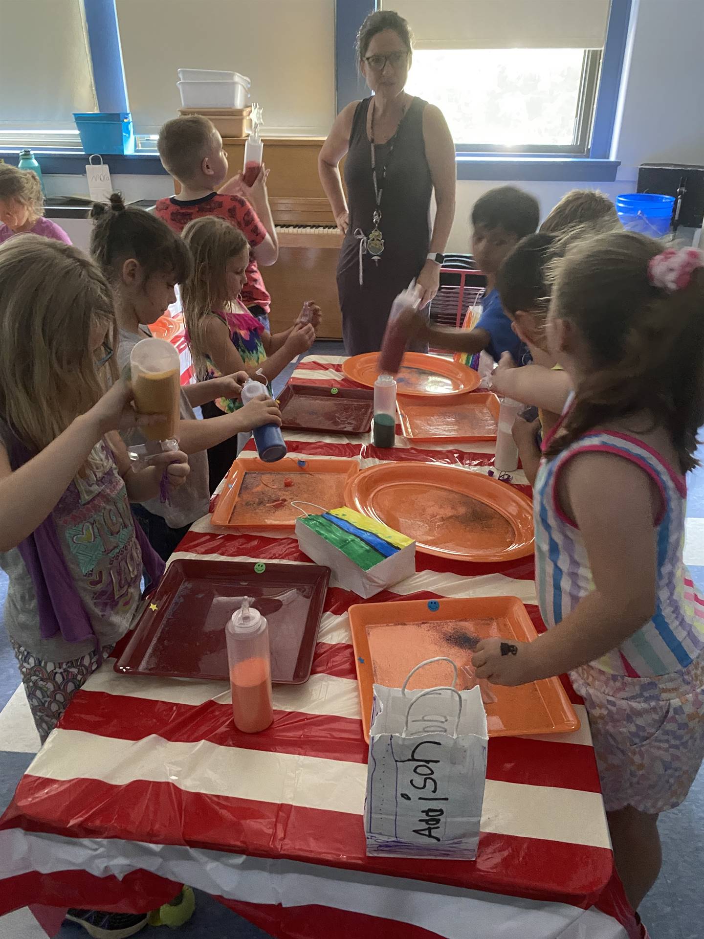 students pour sand out of a bottle to make a sand art craft. 