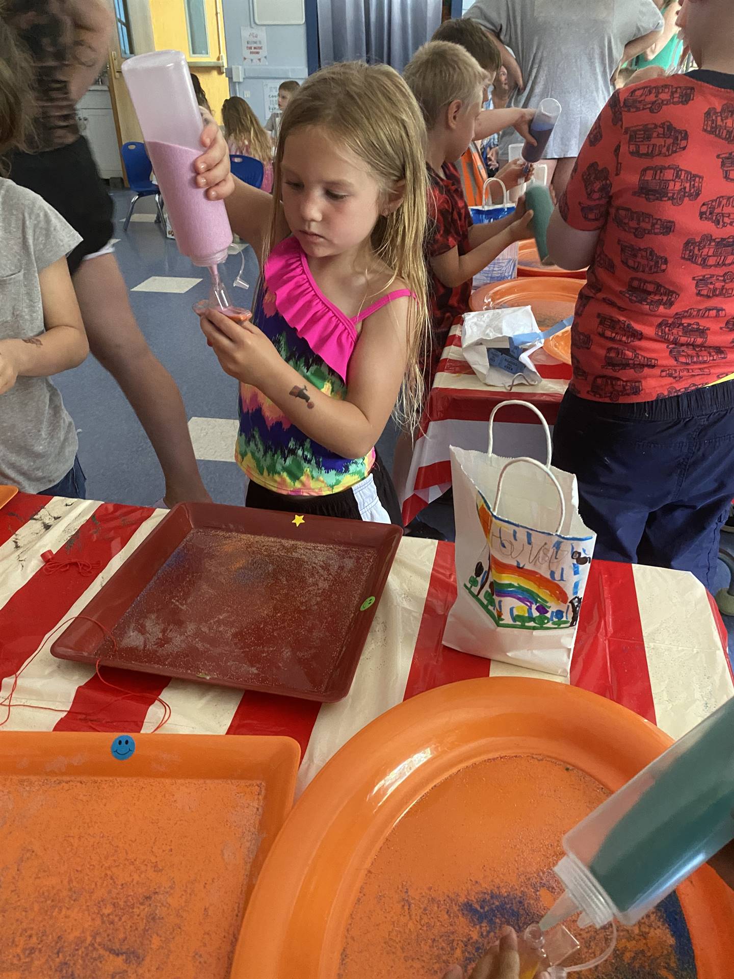 students pour sand out of a bottle to make a sand art craft. 