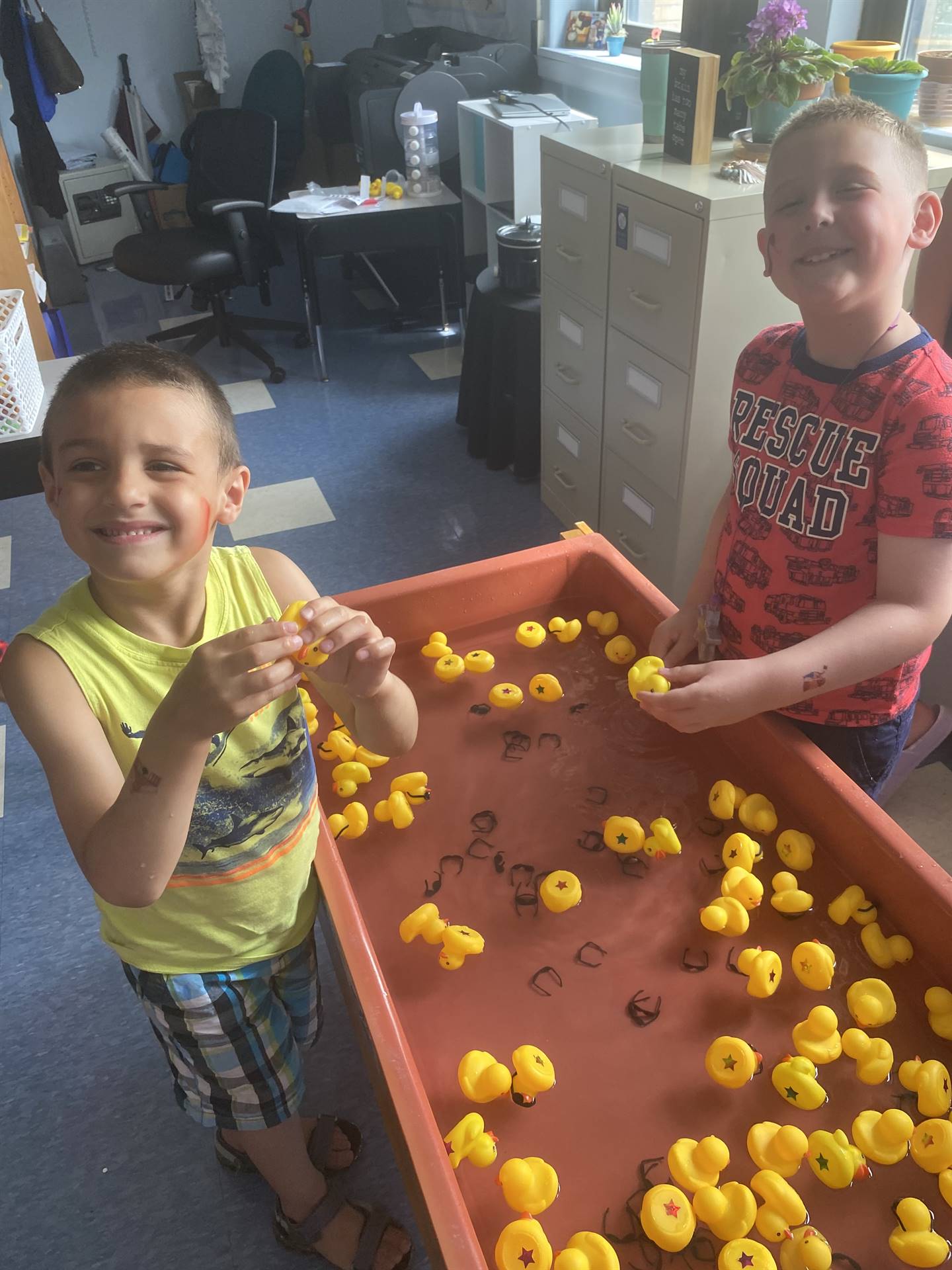 students playing in water filled with yellow rubber duckies.