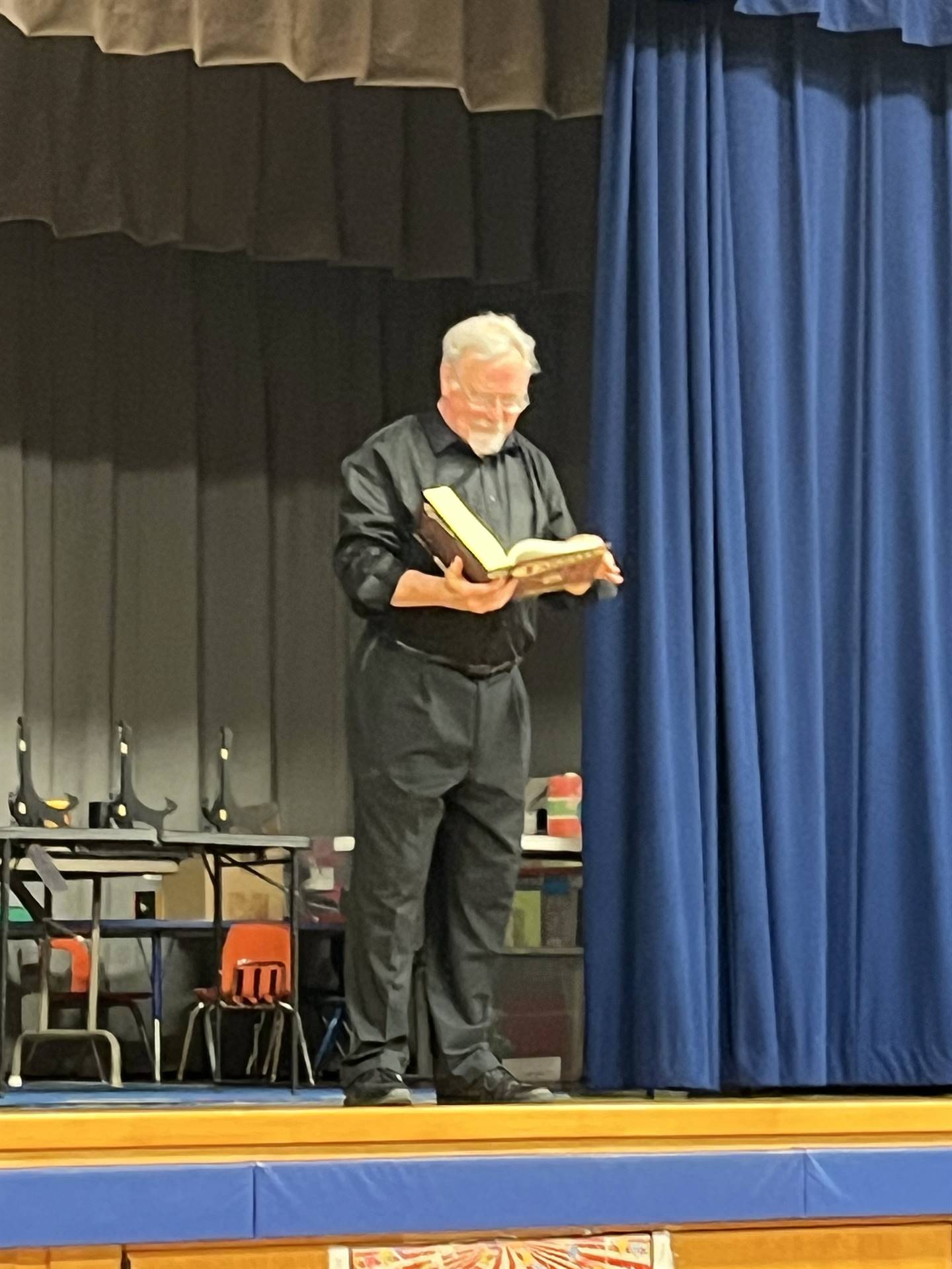 a Magician dressed in black reads from his magic book