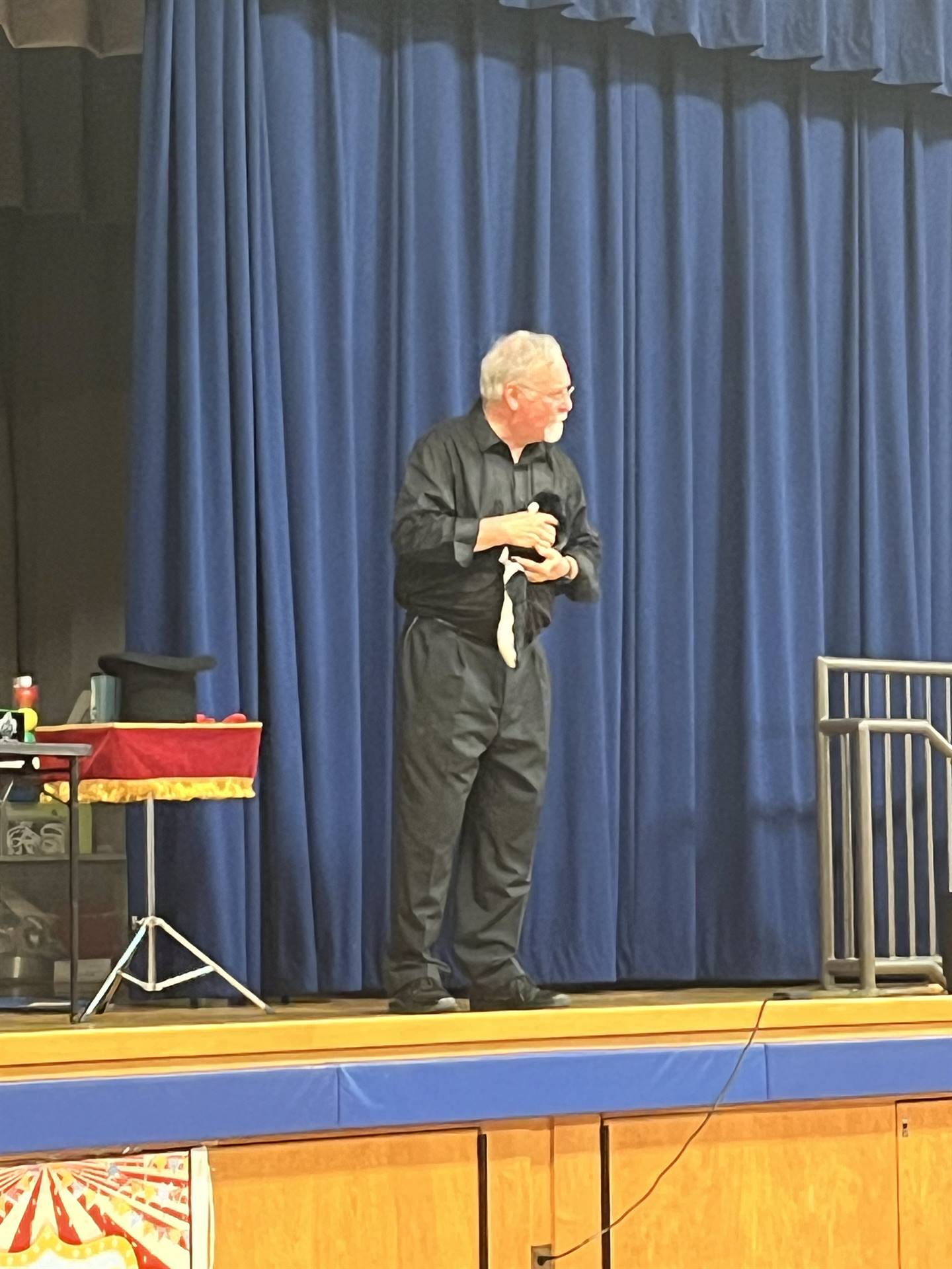a Magician dressed in black shows a baby skunk he pulled from his black hat