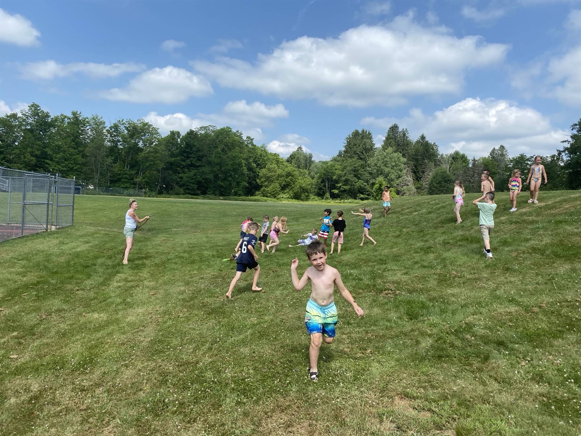 students outdoors throwing darts at balloons.