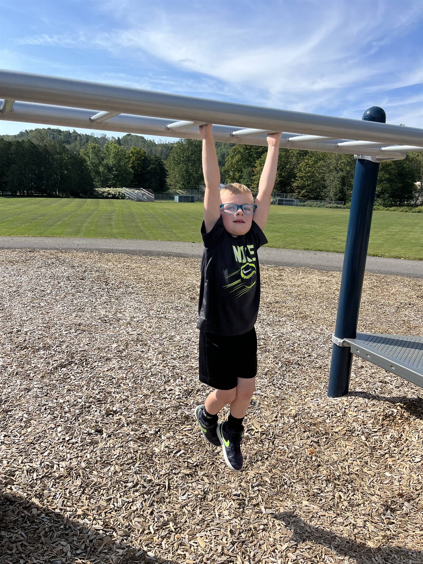 student hanging from monkey bars