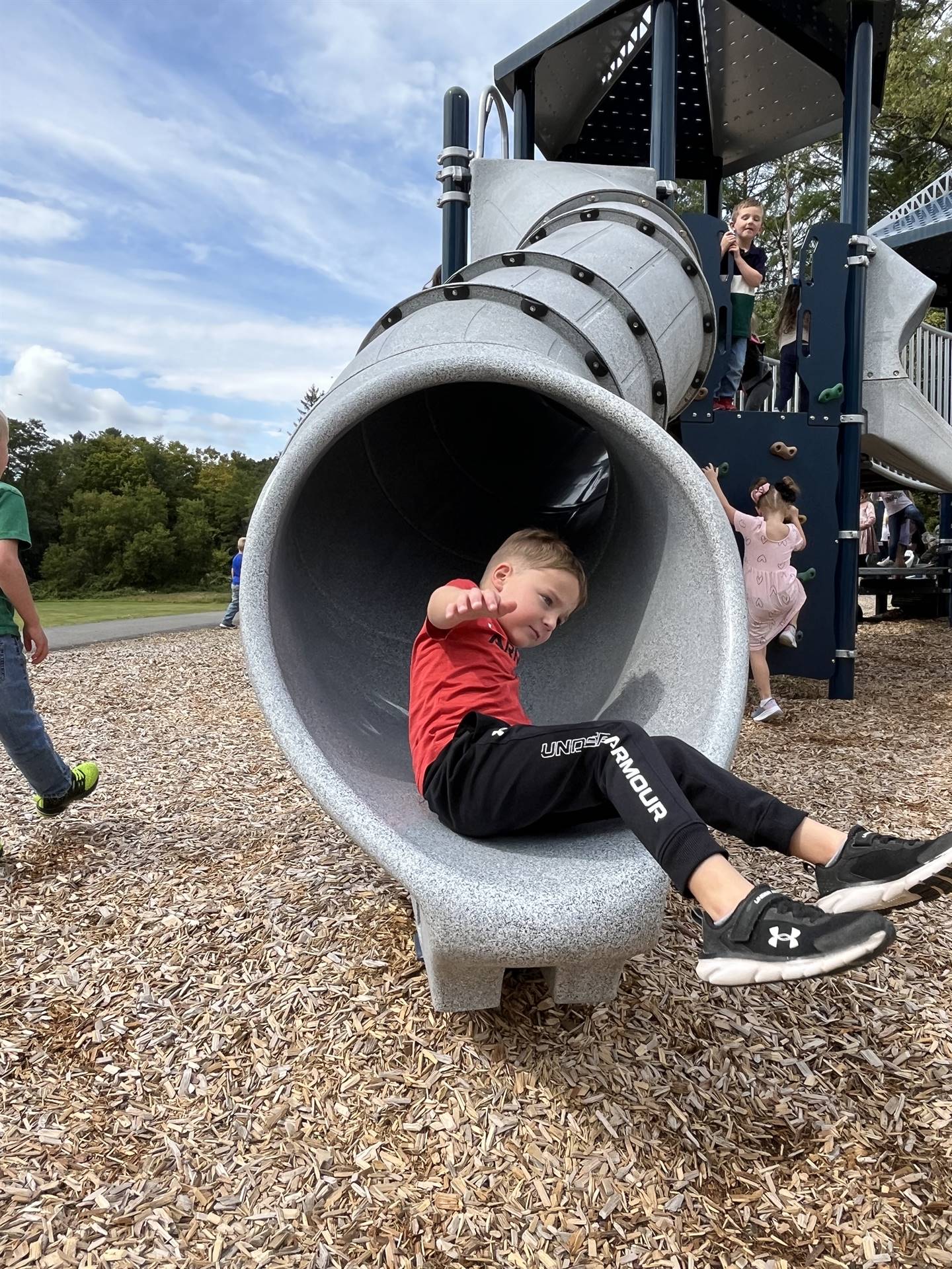 student coming out of a slide tunnel on playground
