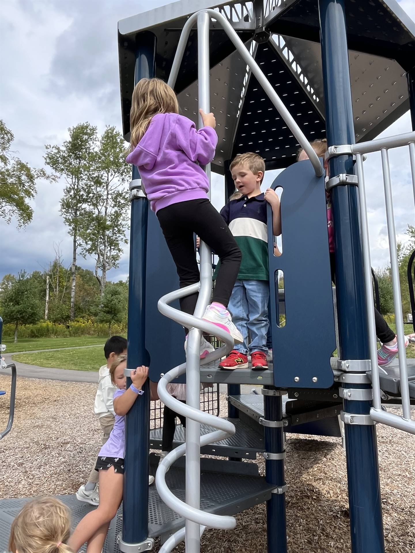 2 students climbing up on apparatus of playground