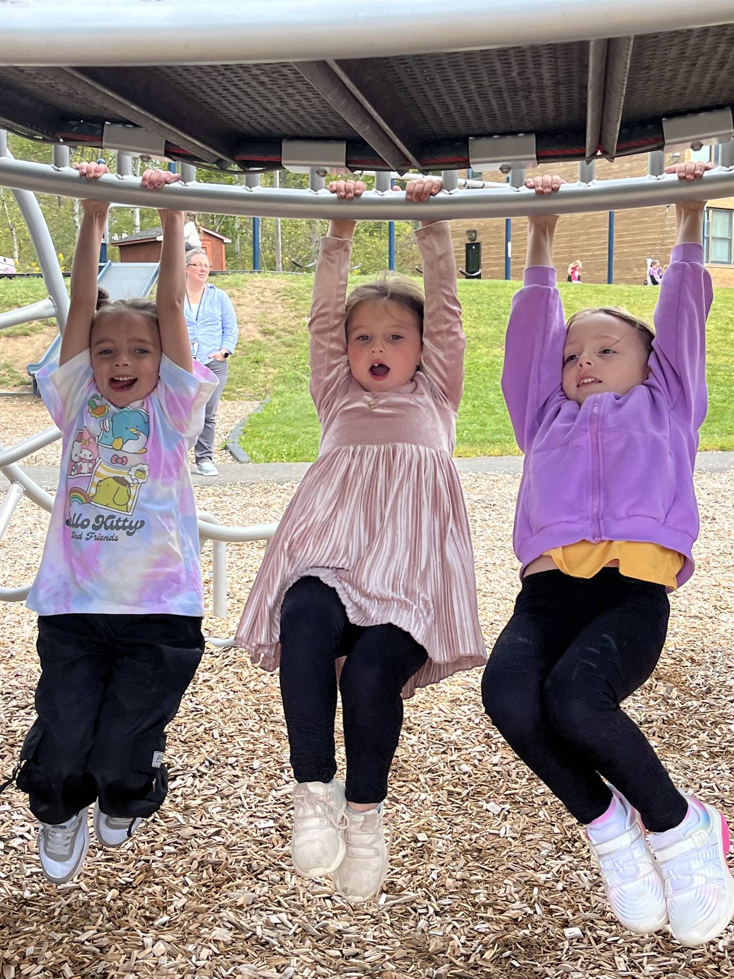 3 students hanging on monkey bars