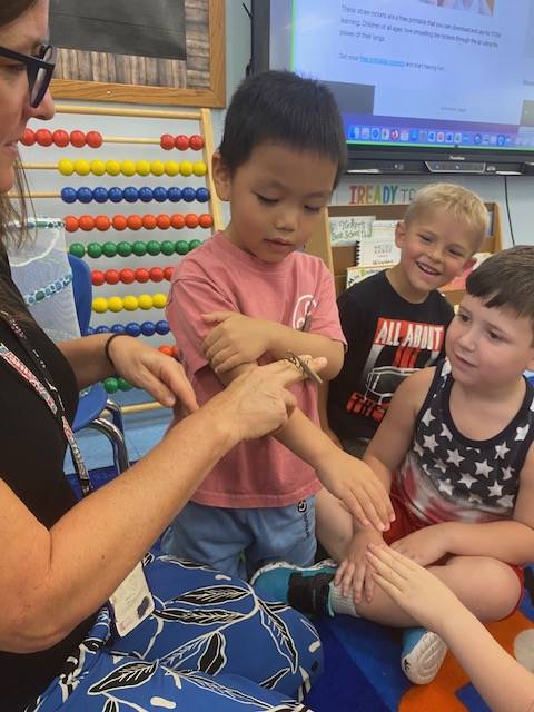 teacher with praying mantis on fingers and students watching
