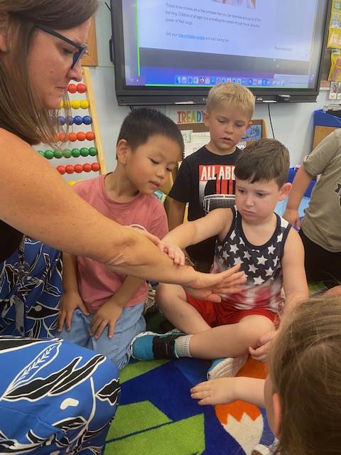 teacher with praying mantis on fingers and students watching