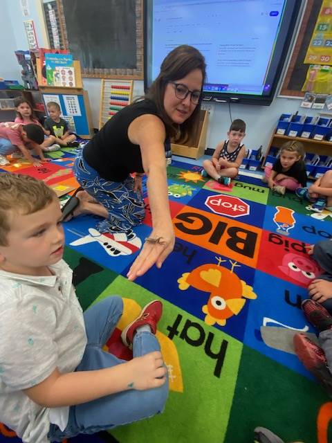 teacher with praying mantis on fingers and students watching