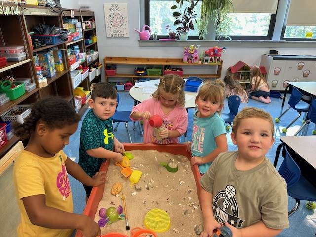 a group of students play in sandbox together.