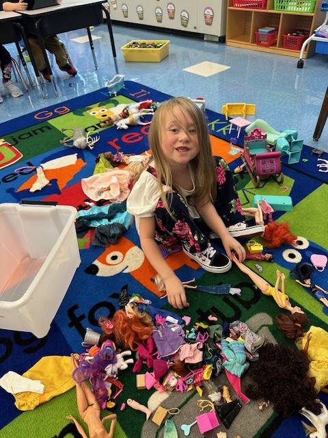 a student is playing with a variety of toy dolls