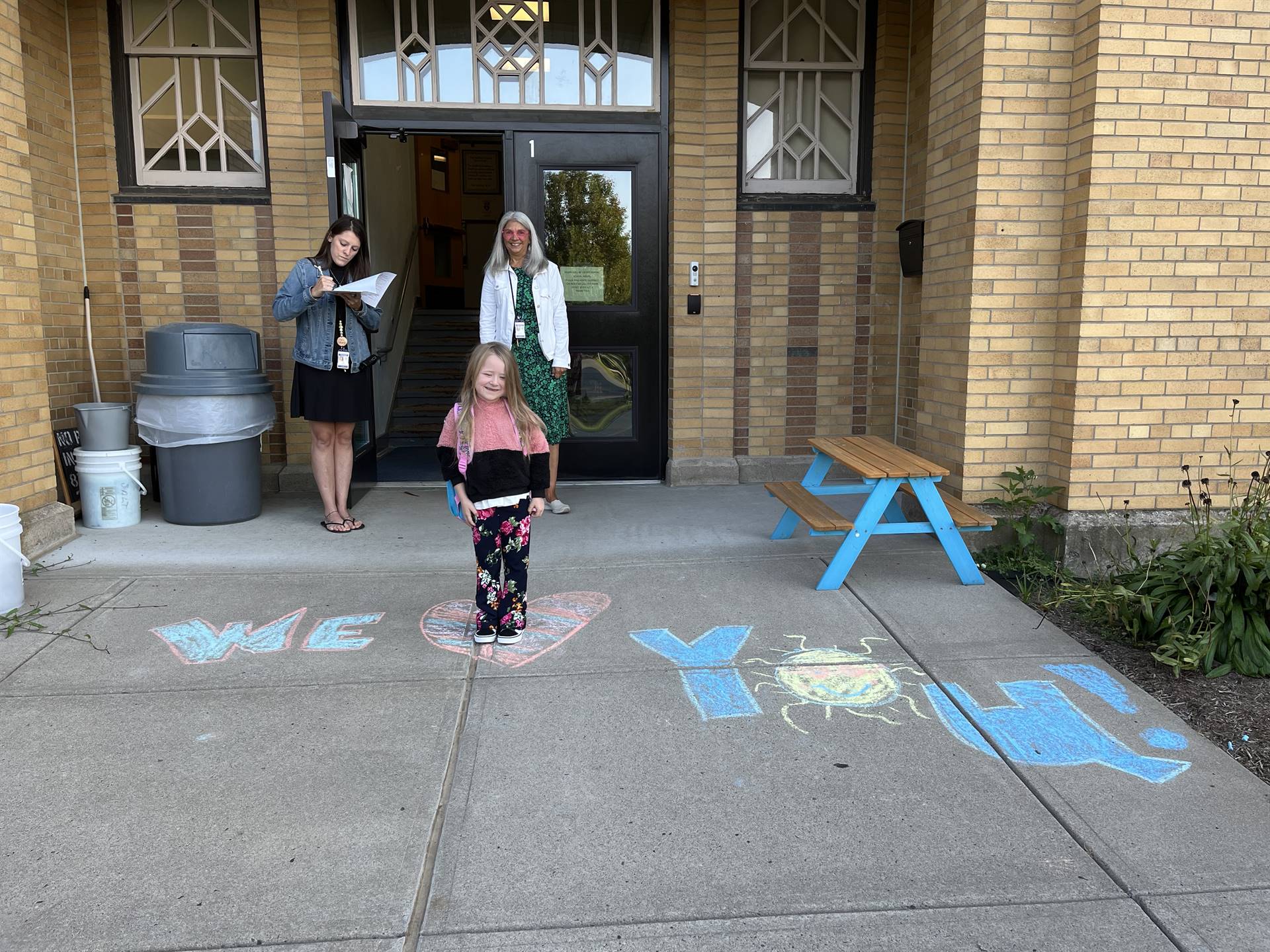 student and adult on sidewalk chalk heart in front of school doorway