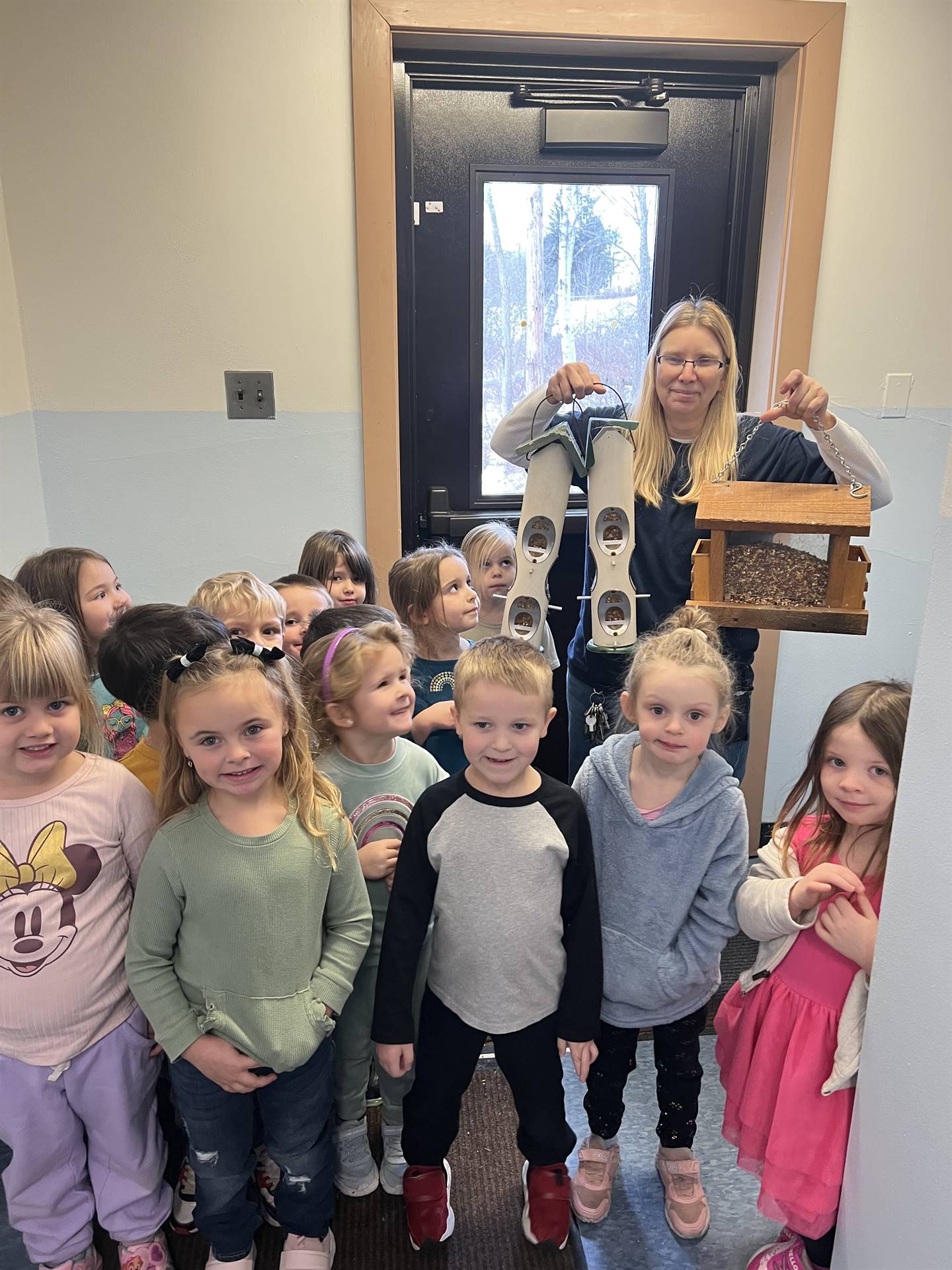 students with a staff member holding a bird feeder