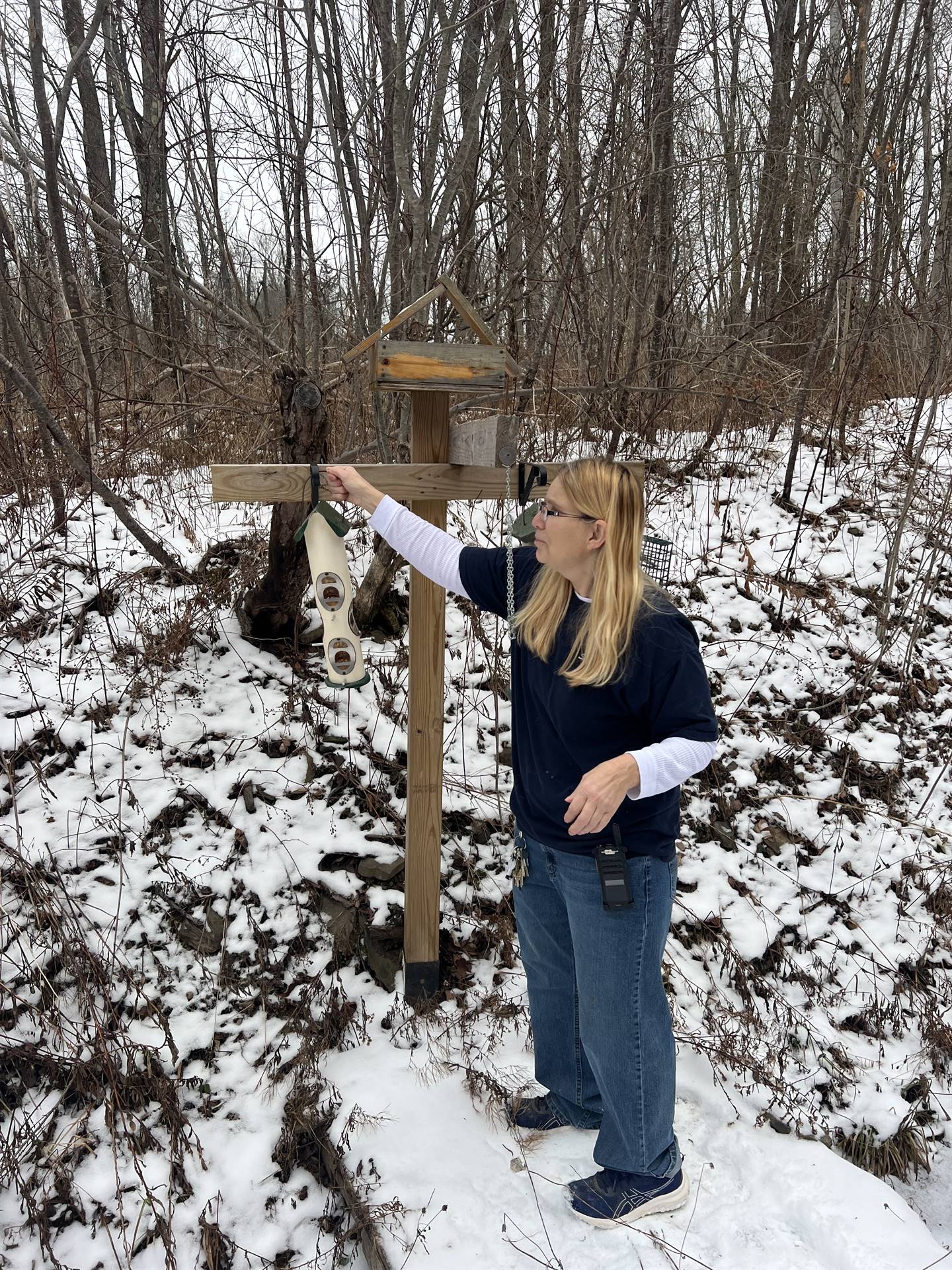 A staff member hangs up a bird feeder that has been filled by students.