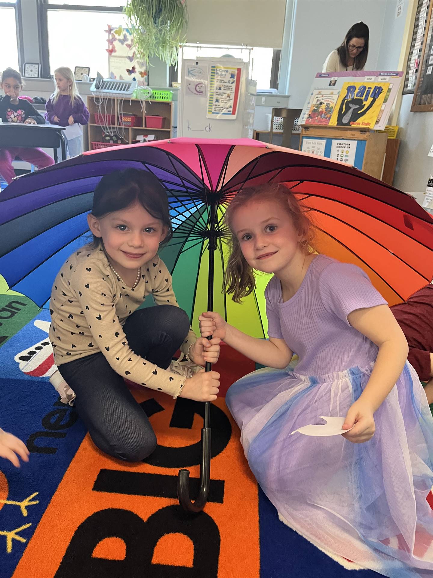 2 students under a rainbow umbrella