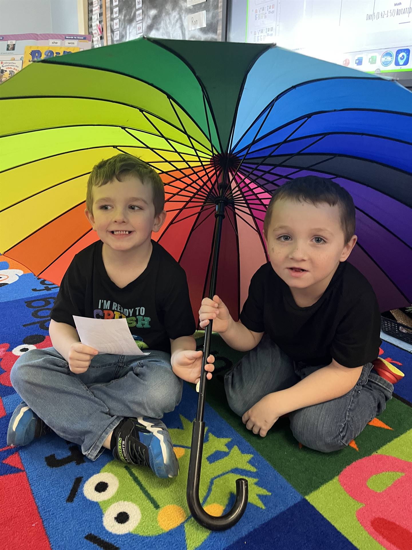 2 students under a rainbow umbrella