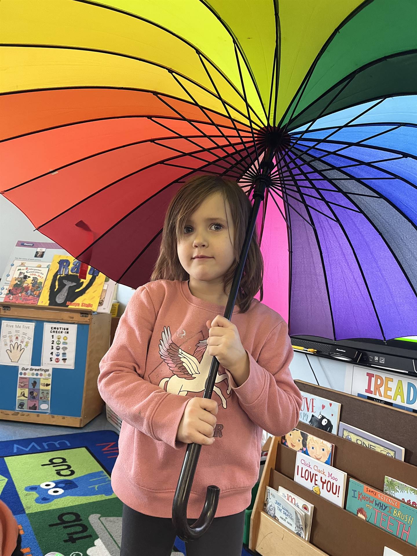 A student under a rainbow umbrella