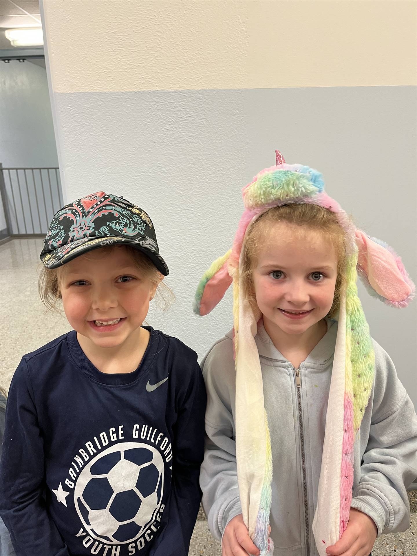 A student with a bunny ear hat and another student with a baseball cap