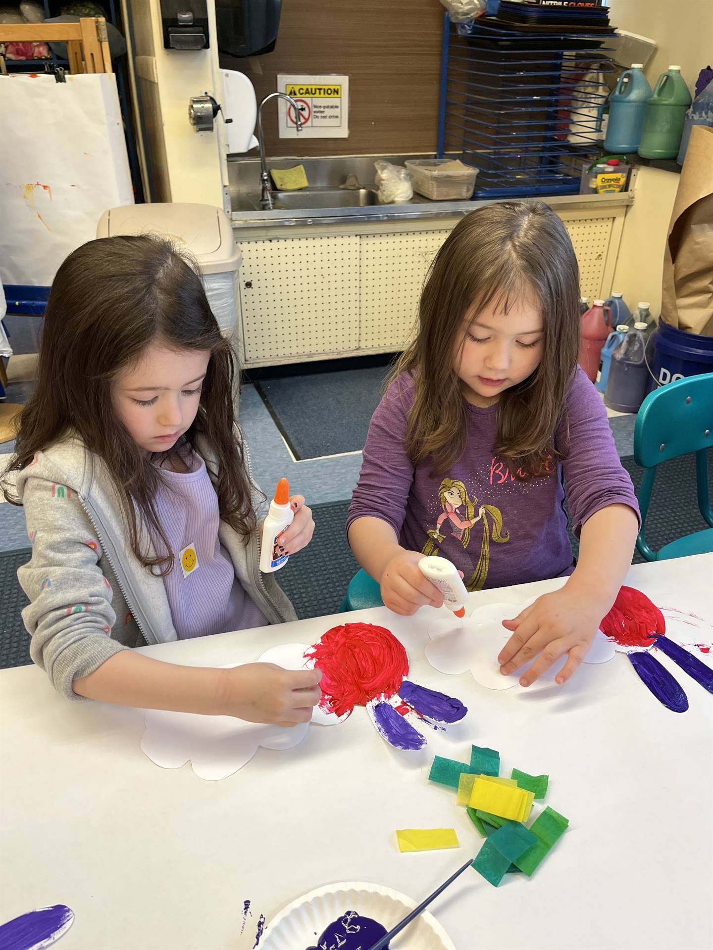 2 students paint a caterpillar head