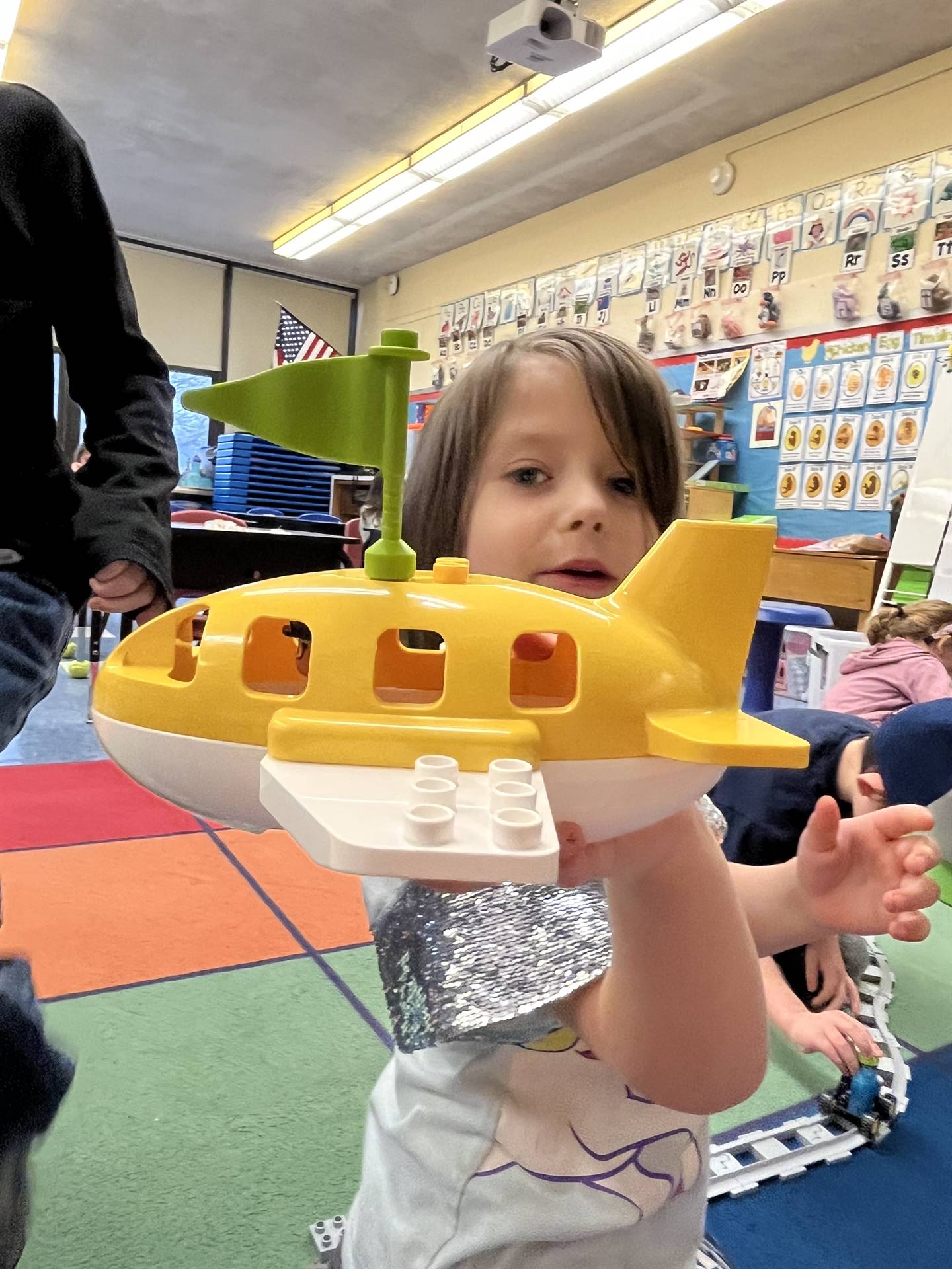  student holds up a yellow toy airplane