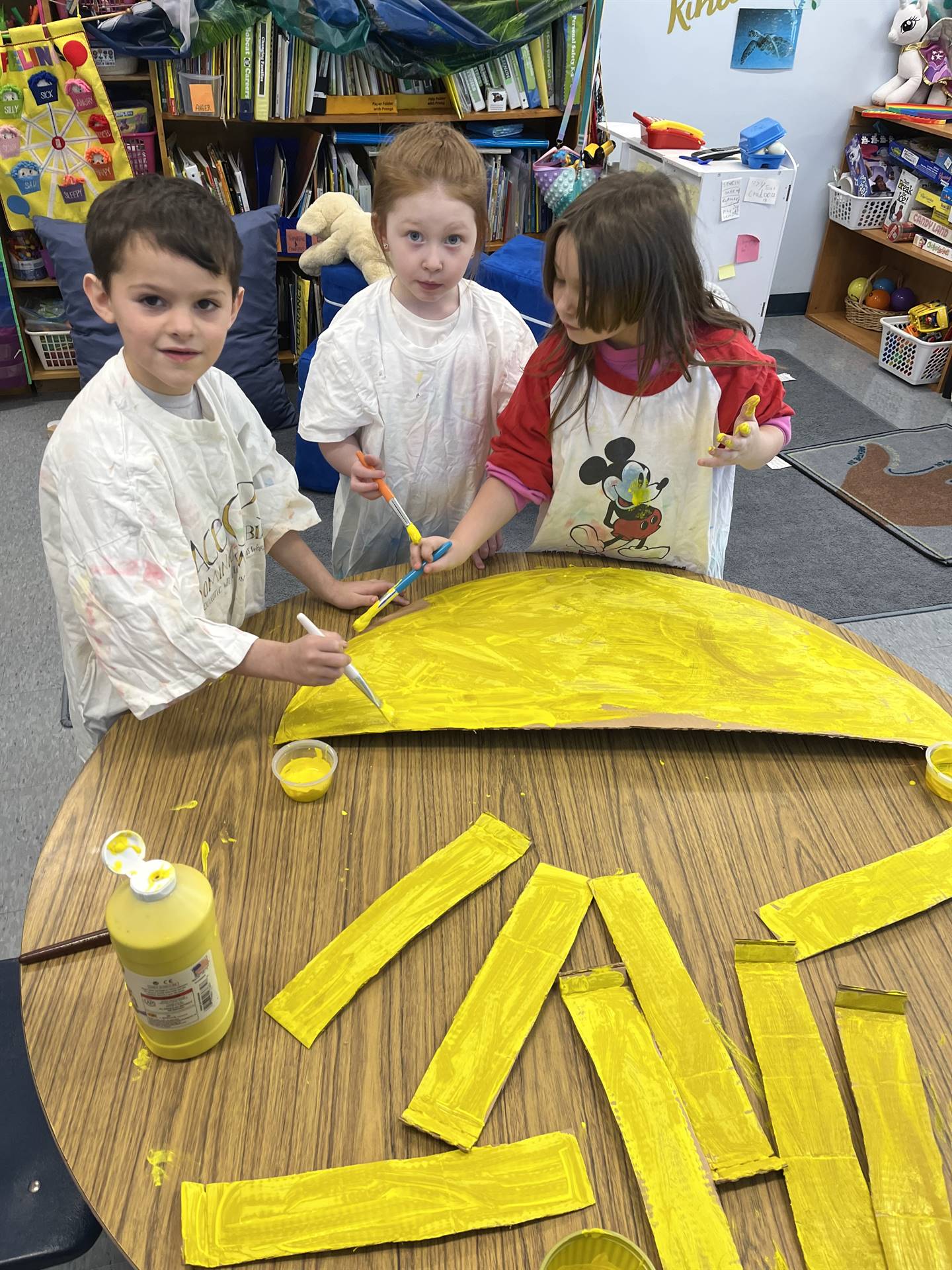 3 students assist in painting a prop for the school play.