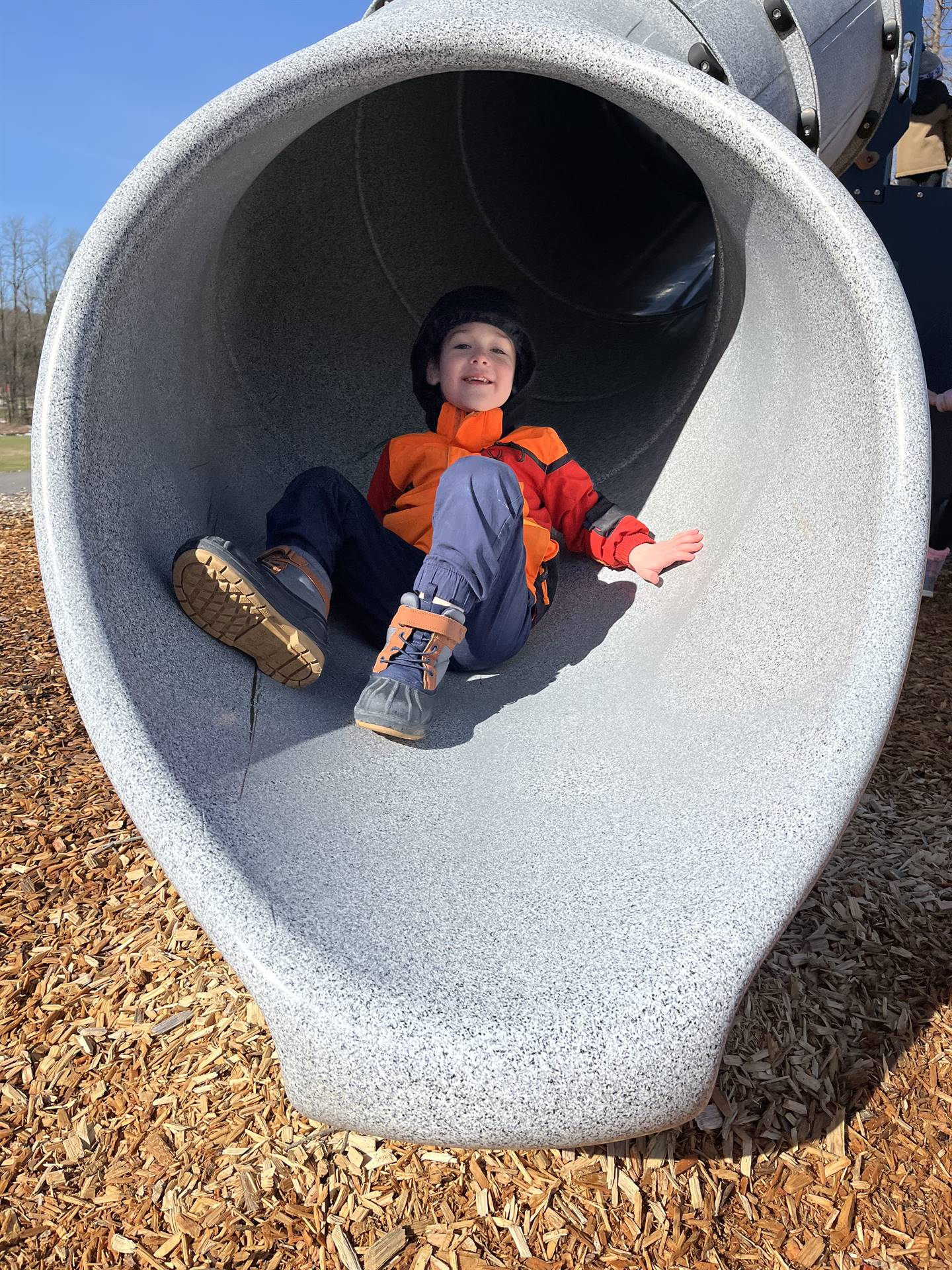 a student at the end of a round slide tunnel