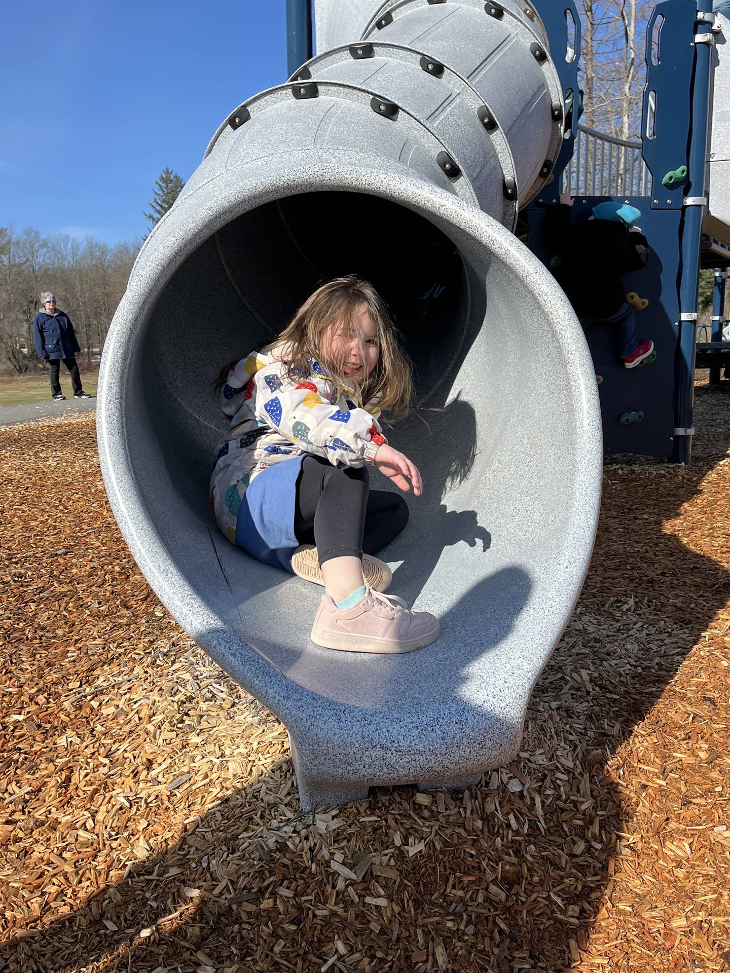 a student at the end of a round slide tunnel